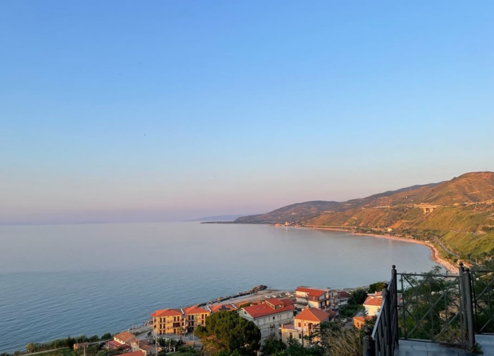 Die Küste bei Marina di Caronia in der Abenddämmerung, Meer und Ortschaft unter den Hügeln Nordsiziliens