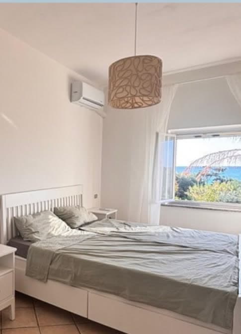 Schlafzimmer mit Doppelbett und Fenster mit Meerblick