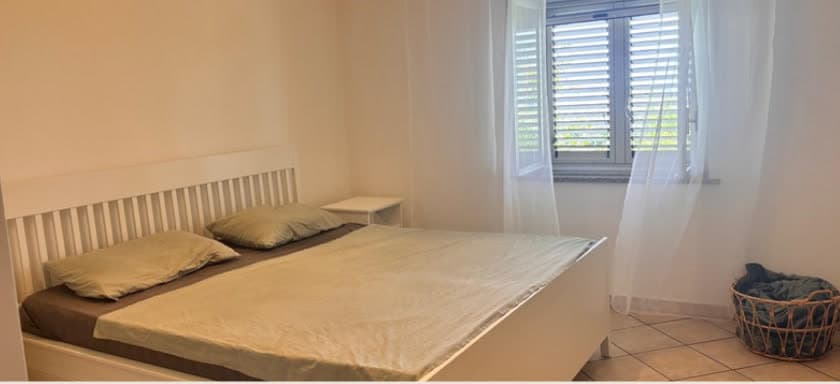 Schlafzimmer mit weißen Vorhängen und Fensterläden