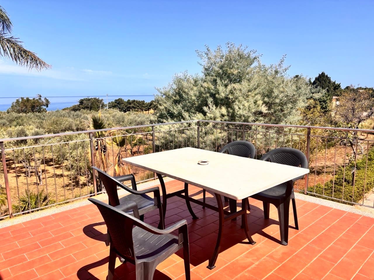 Terrasse mit Esstisch, Blick über Olivenbäume auf das Meer