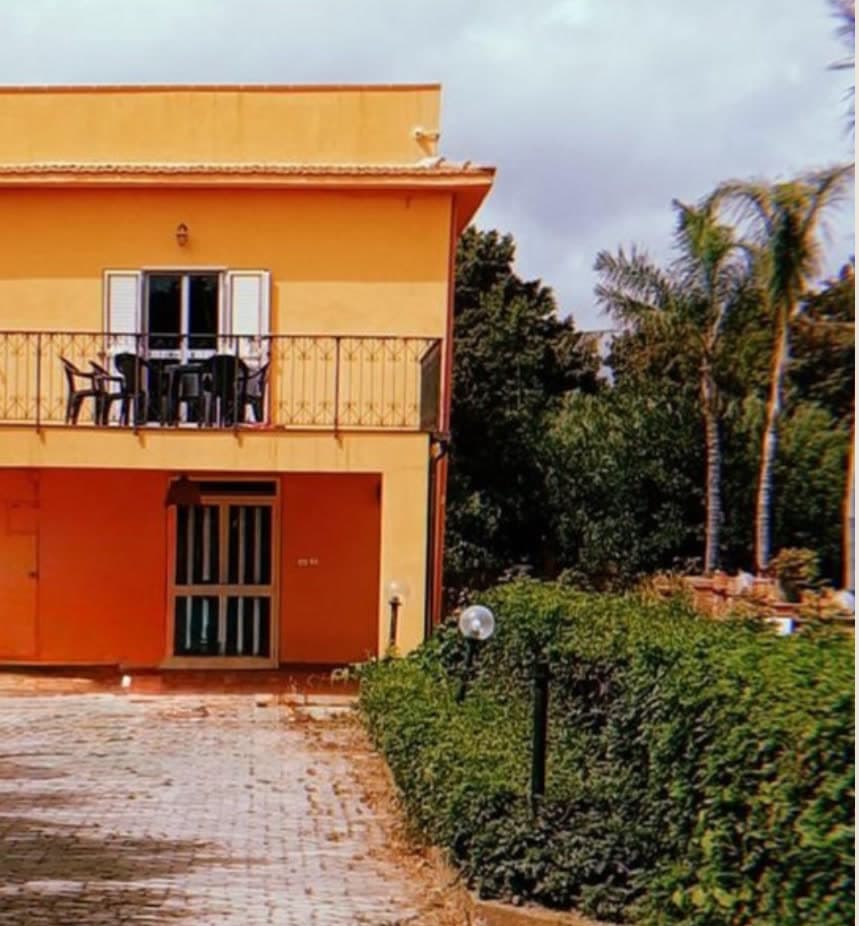 Das gelbe Gebäude von Casa Piana mit Balkon, umgeben von Palmen und Grün